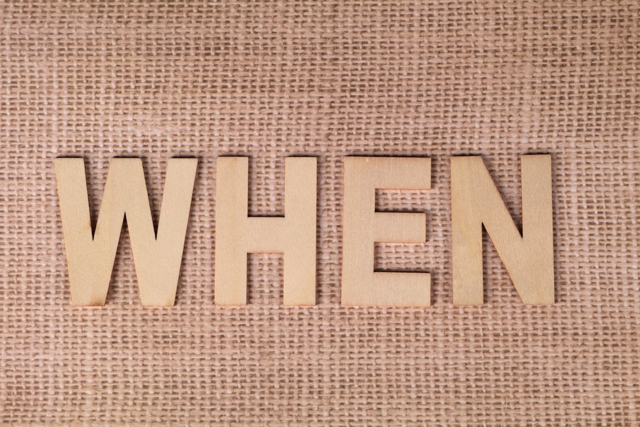 our-story-02 Wooden letters spelling "WHEN" on a textured burlap surface, ideal for concepts of time and planning.
