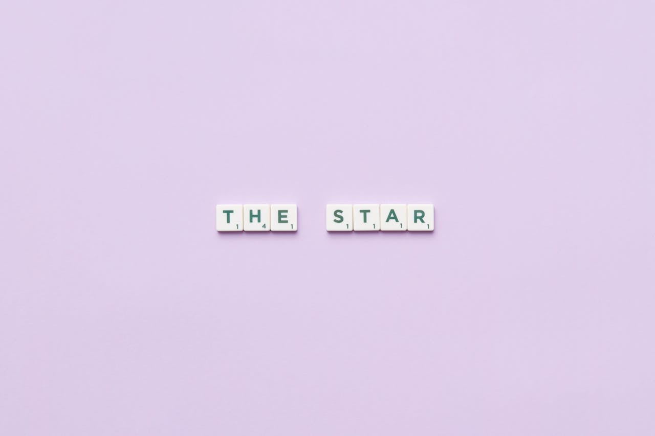 our-story-01 Scrabble tiles spelling 'The Star' on a soft pastel background, providing clean copy space.