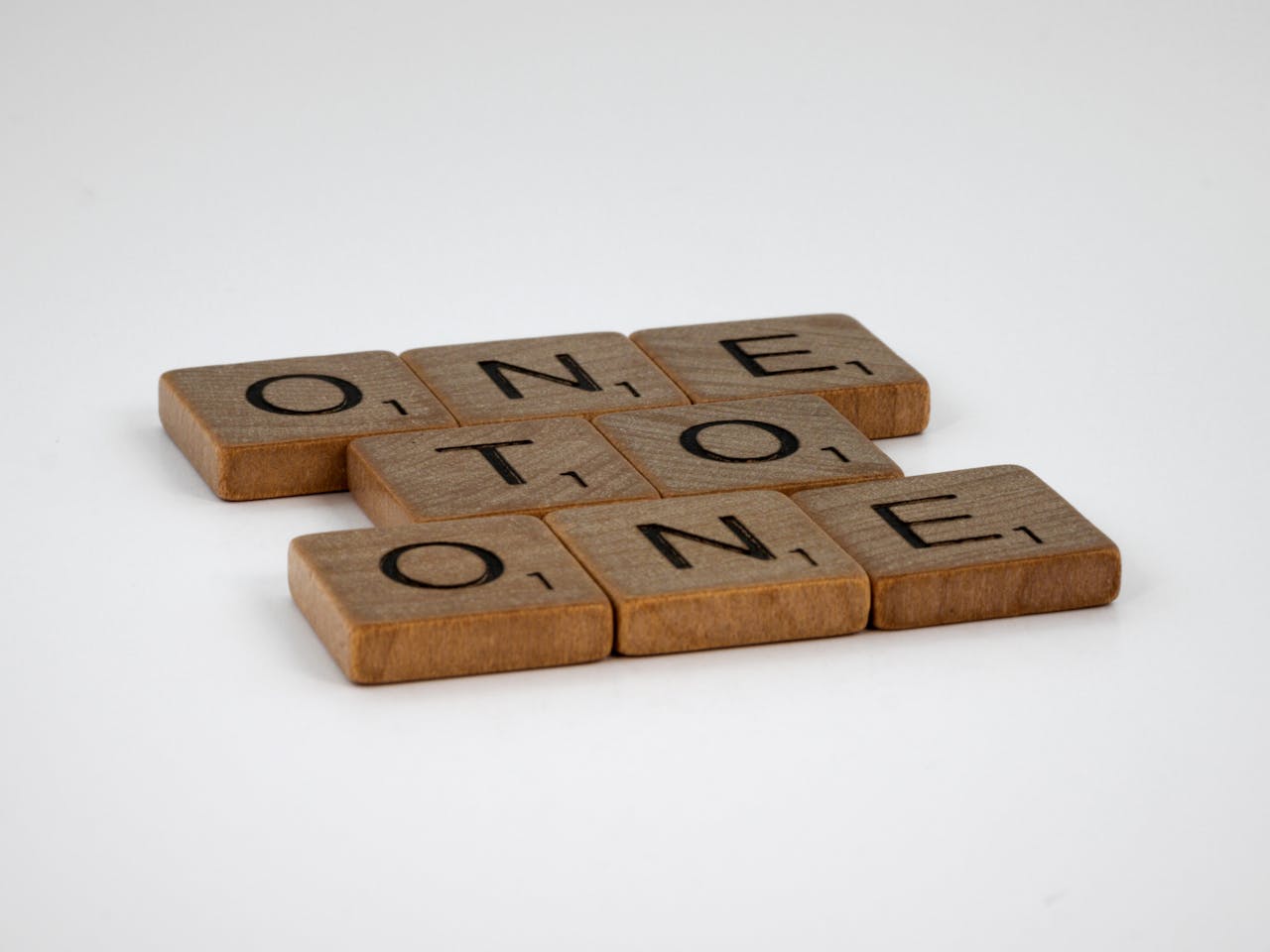 Close-up of wooden Scrabble tiles arranged to spell out words on white surface.